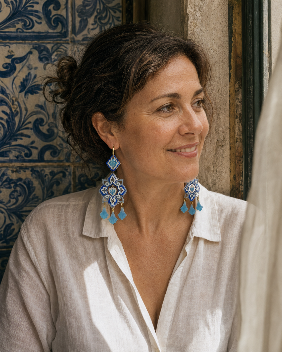 Retrato artístico con los pendientes Alma de Oporto junto a una ventana y azulejos portugueses.