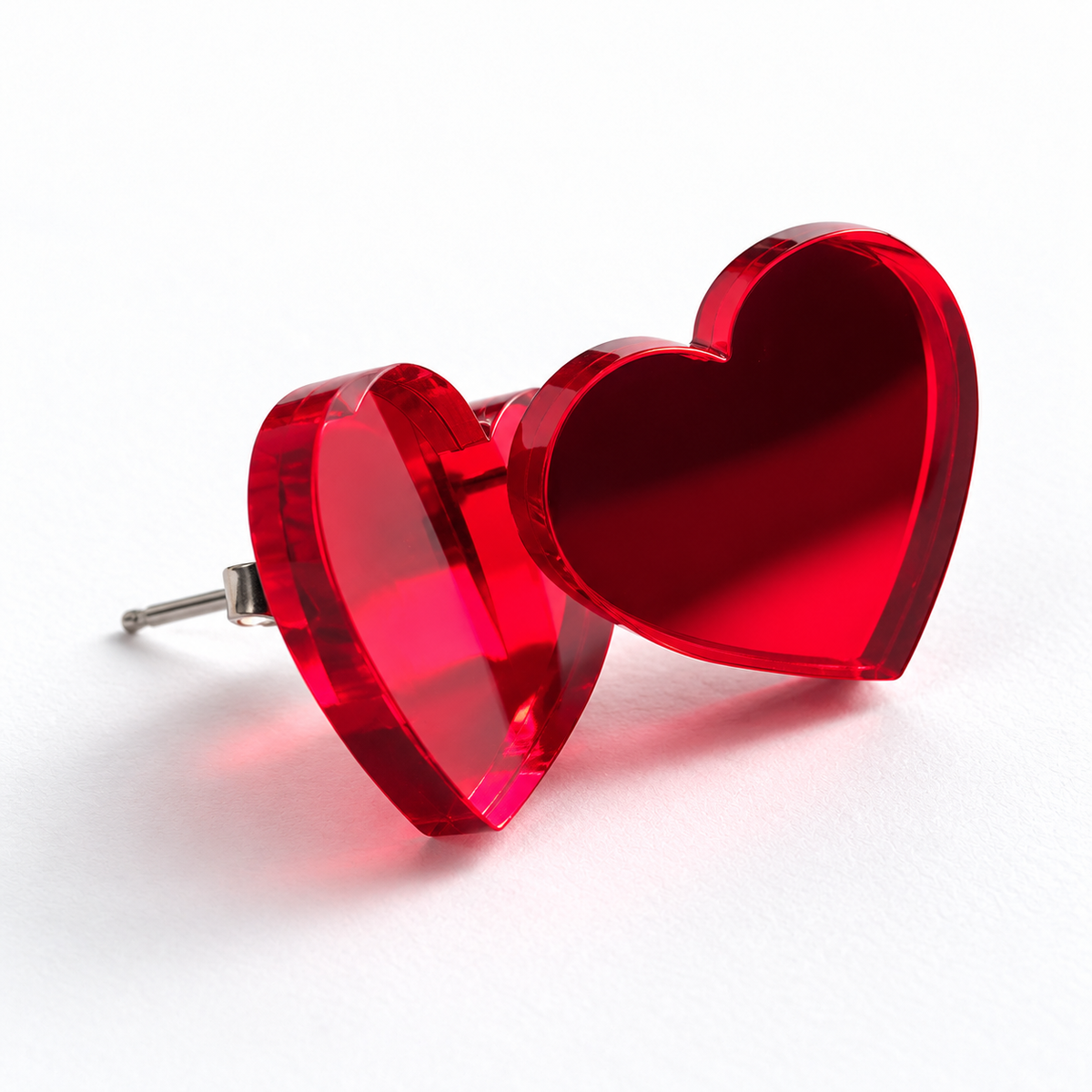 Par de pendientes de botón en forma de corazón, en metacrilato rojo espejo, fotografiados sobre fondo blanco limpio.