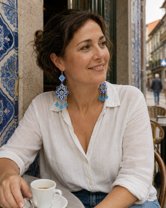 Pendientes Alma de Oporto combinados con una blusa blanca de lino en una escena de café de inspiración portuguesa.