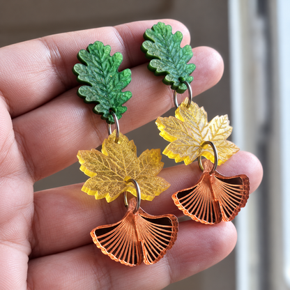 Par de pendientes Danza de Hojas en la mano: verde nacarado, amarillo con glitter y espejo cobre.