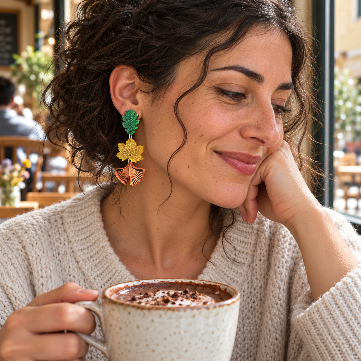 Pendiente Danza de Hojas de 7 cm puesto, en una escena de cafetería con chocolate caliente.
