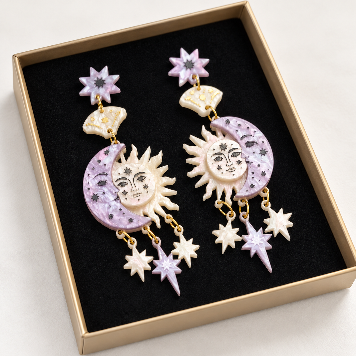 Pareja de pendientes de sol y luna lila y nácar en su caja con borde dorado
