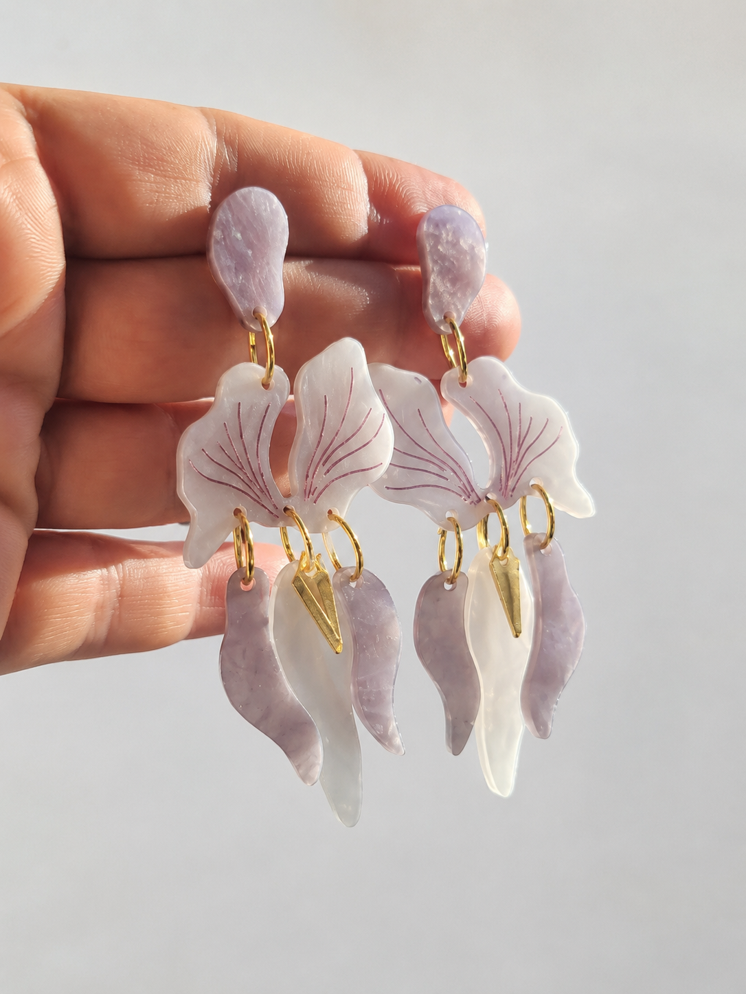 Pendientes Orquídea Nácar Violeta sostenidos en la mano