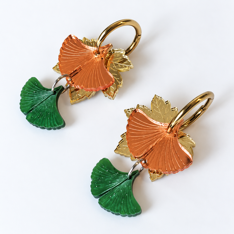 Pendientes Brisa de Otoño de Sergi Bastian, con hojas doradas, ginkgo cobrizo y verde nacarado sobre fondo blanco