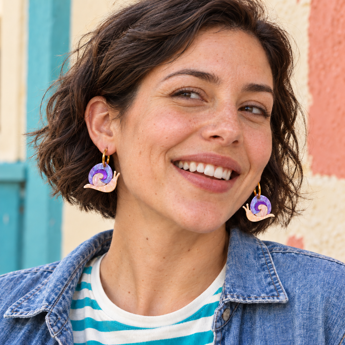 Pendientes Caracoles Mágicos puestos en una mujer de estilo casual, con espejo lila intenso; vista orientativa del tamaño.