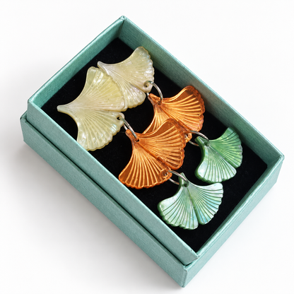 Par de pendientes Ginkgo de Otoño en su caja turquesa con interior negro.