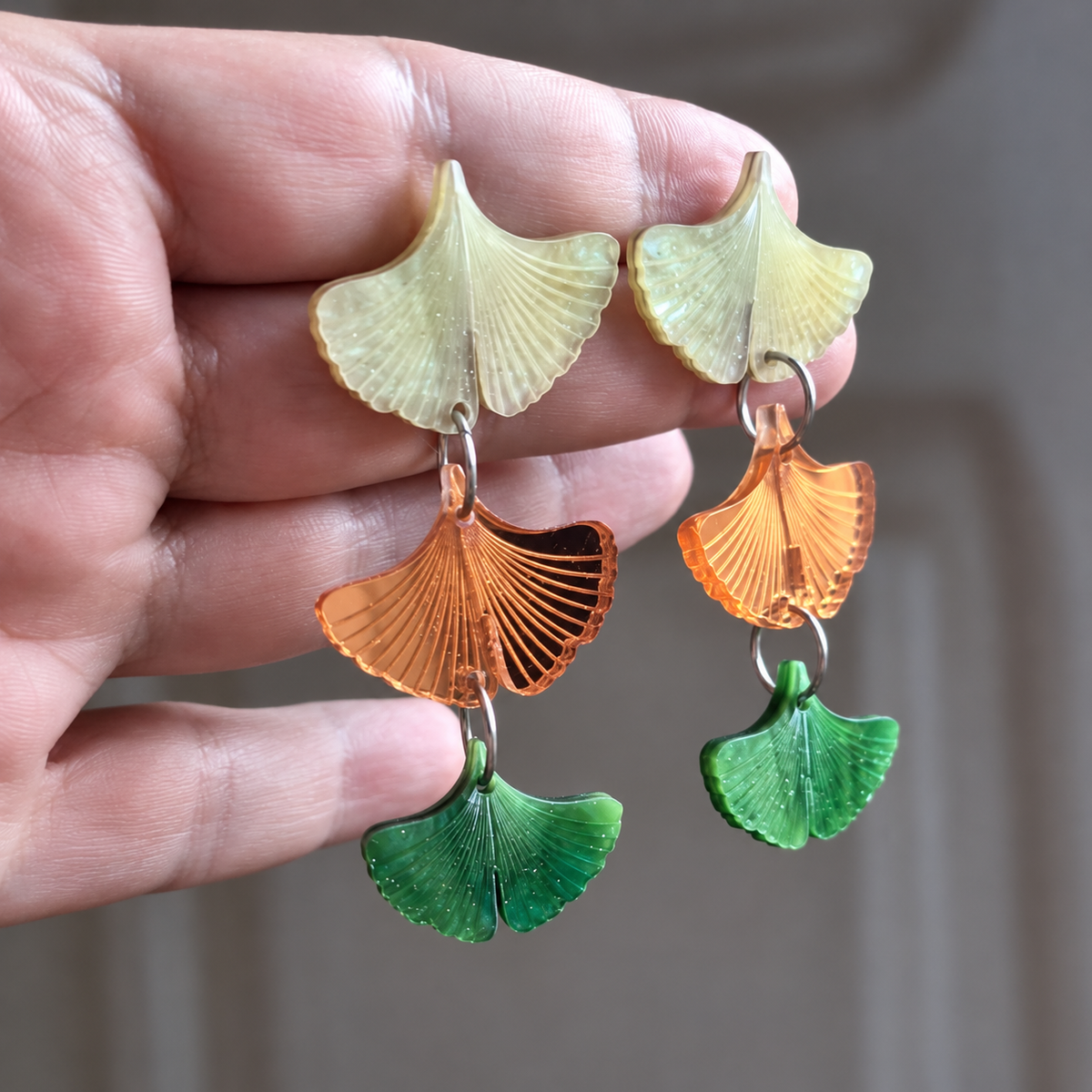 Detalle de las hojas de ginkgo nacaradas, el espejo naranja y las aguas del verde, sostenidas en la mano.