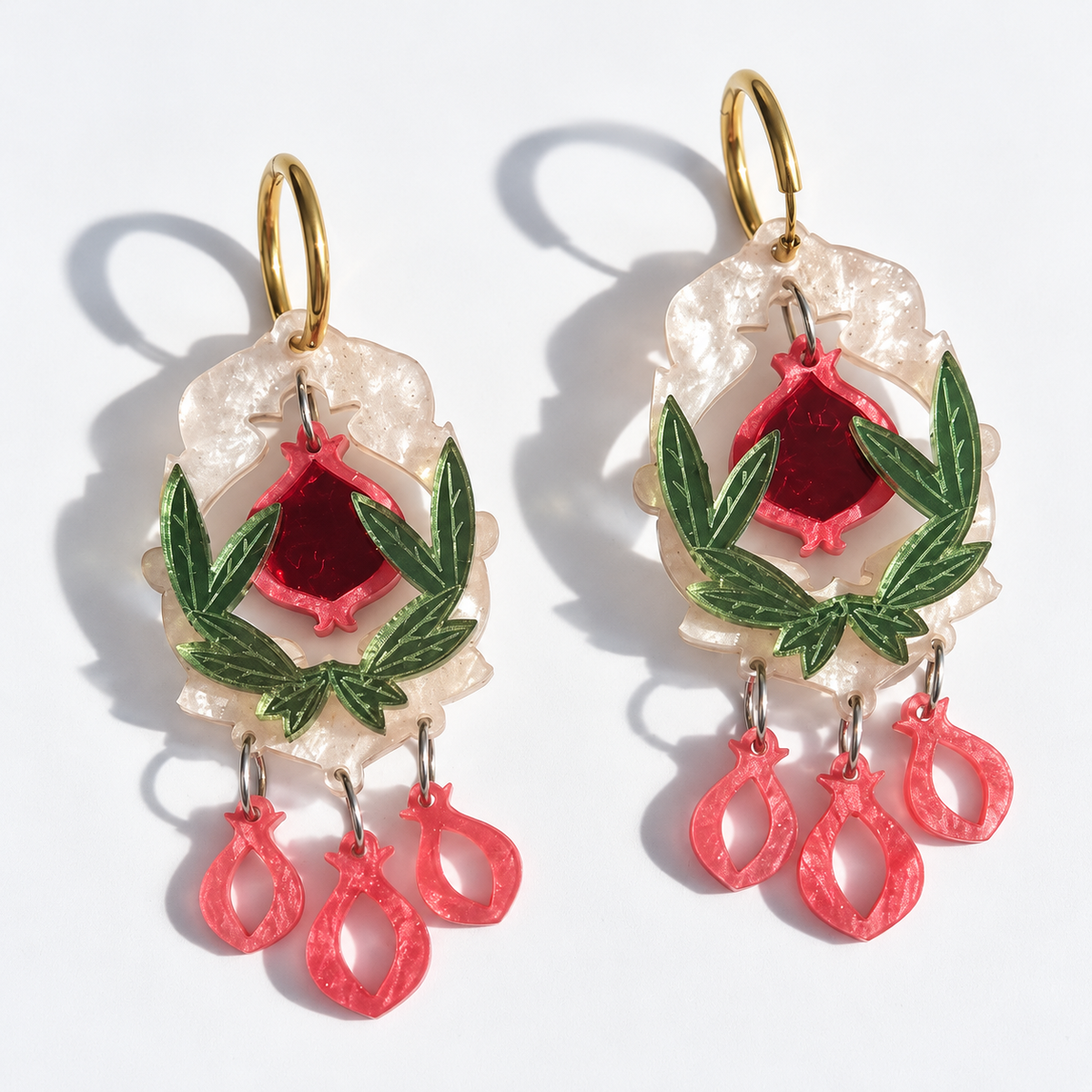 Pendientes Jardín de Granadas de Sergi Bastian, con granada roja espejo, hojas verde oliva y marco blanco Galaxy nacarado.