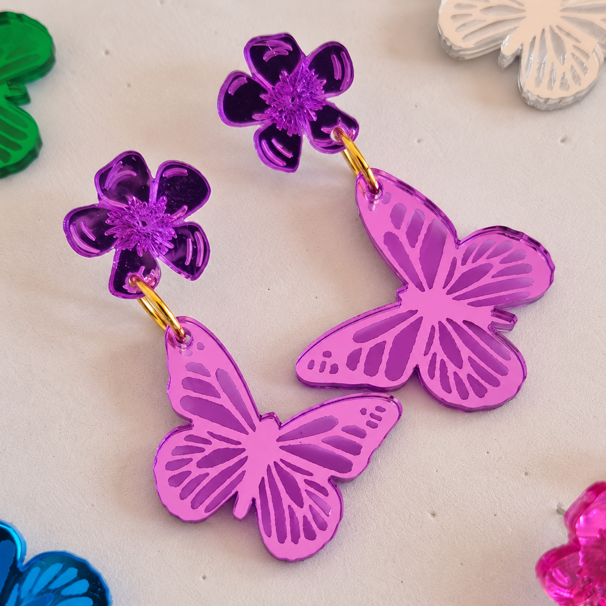 Detalle real de los Pendientes Mariposa violeta espejo, en formato cuadrado