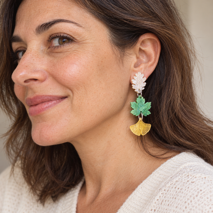 Pendientes Savia del Bosque puestos en una mujer, con tres hojas articuladas en blanco, verde y amarillo.