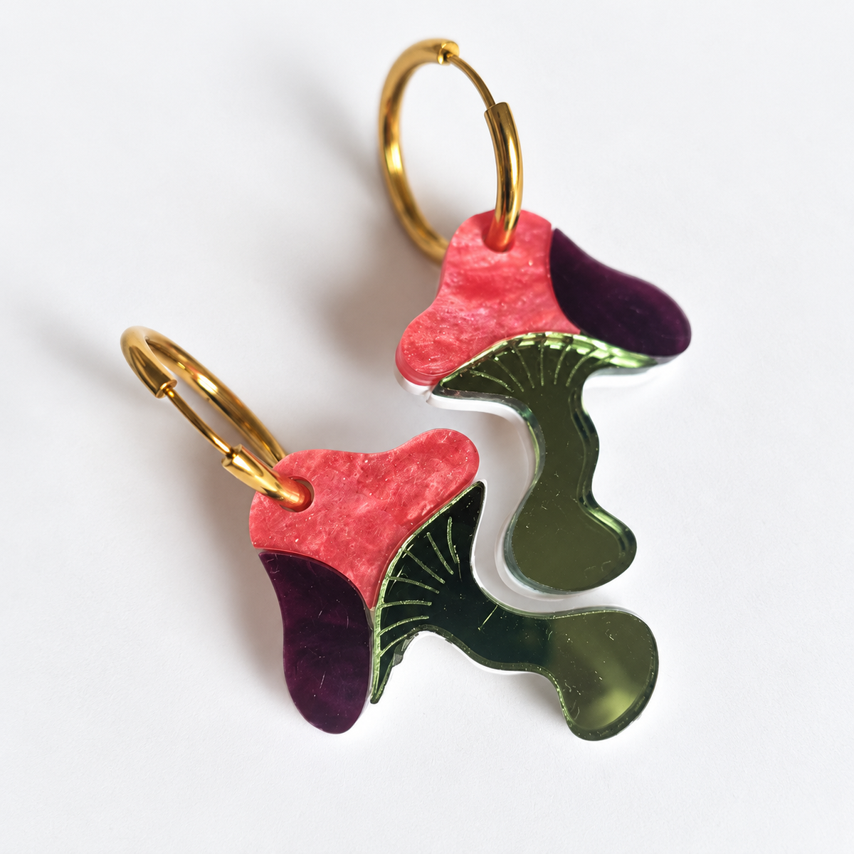 Pendientes Setas del Bosque Encantado de Sergi Bastian, en metacrilato nacarado coral, espejo oliva y espejo ciruela, sobre fondo blanco.