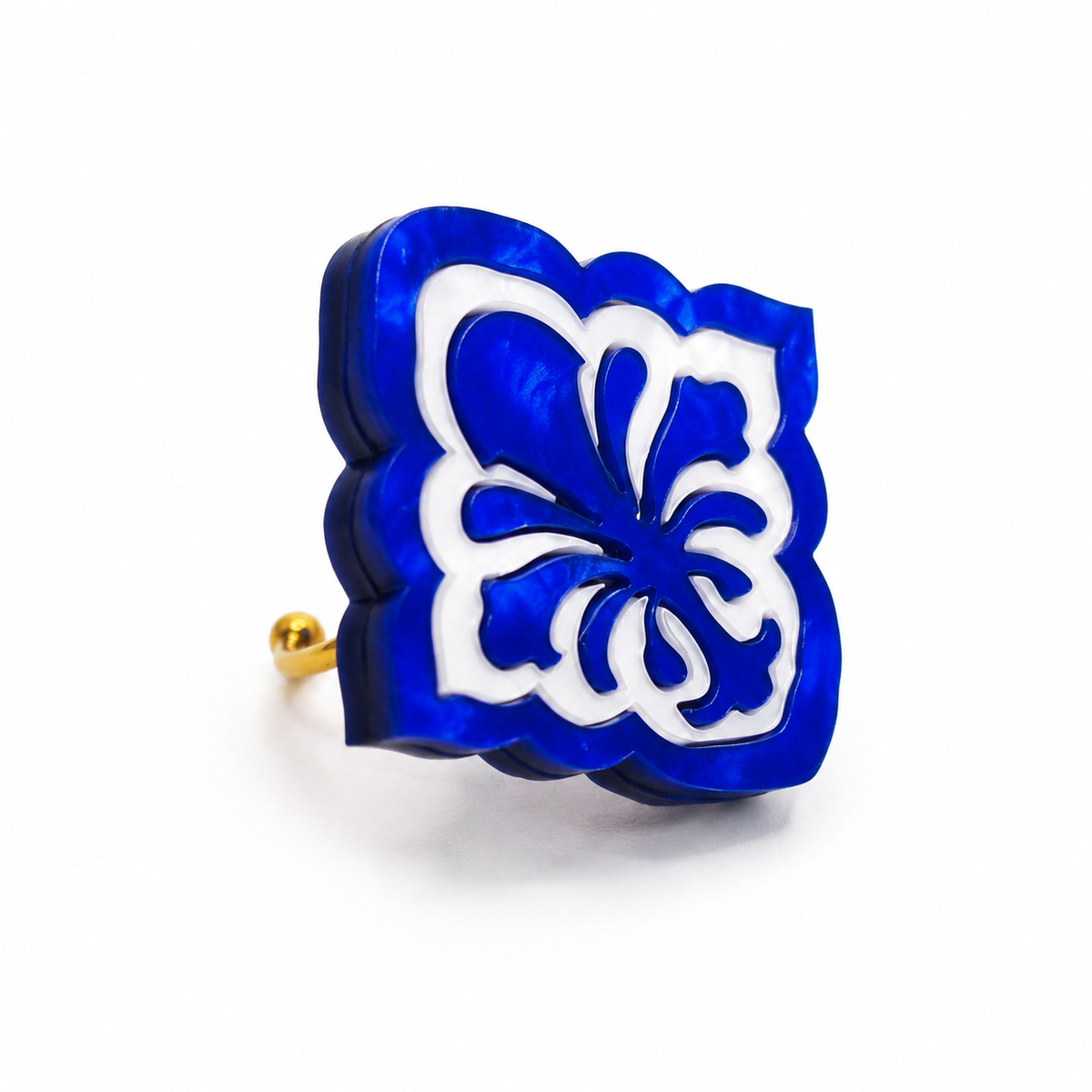 Anillo Flor de Oporto de Sergi Bastian, de 3,5 × 3,5 cm, con motivo floral en metacrilato azul y blanco nacarados y base dorada.
