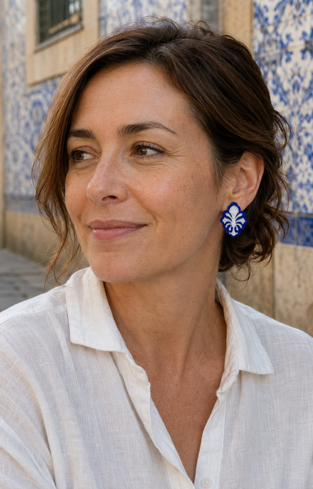Pendientes Flor de Oporto de 3 cm en una mujer con camisa de lino y azulejos portugueses de fondo.
