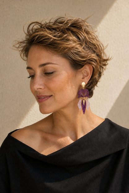 Modelo rubia con pendientes Orquídea lila y rosa en una pose natural; imagen de estilismo generada.