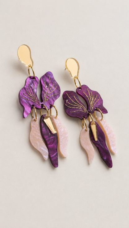 Pendientes Orquídea de metacrilato lila nacarado, rosa glitter nebulosa y espejo dorado, sobre fondo neutro.